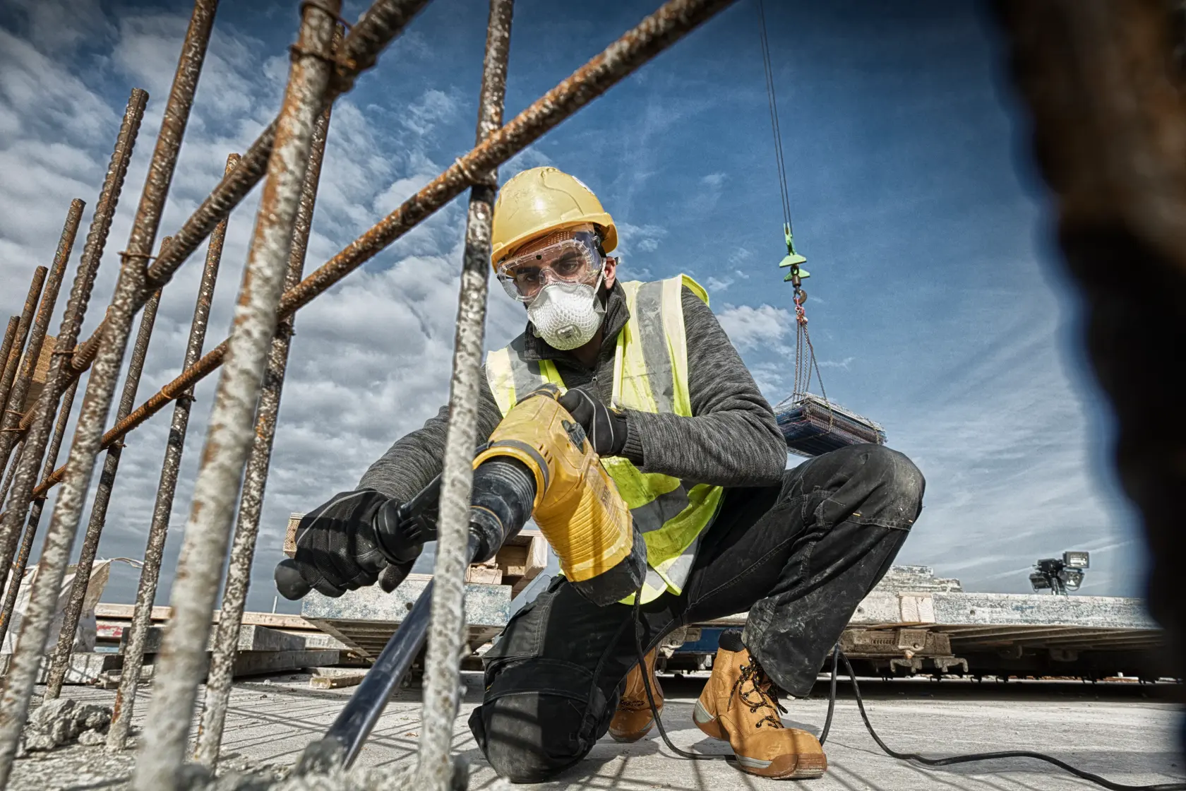 DEWALT D25481K, D25481 martillo rotativo usado en obra; operario perfora concreto entre barras.