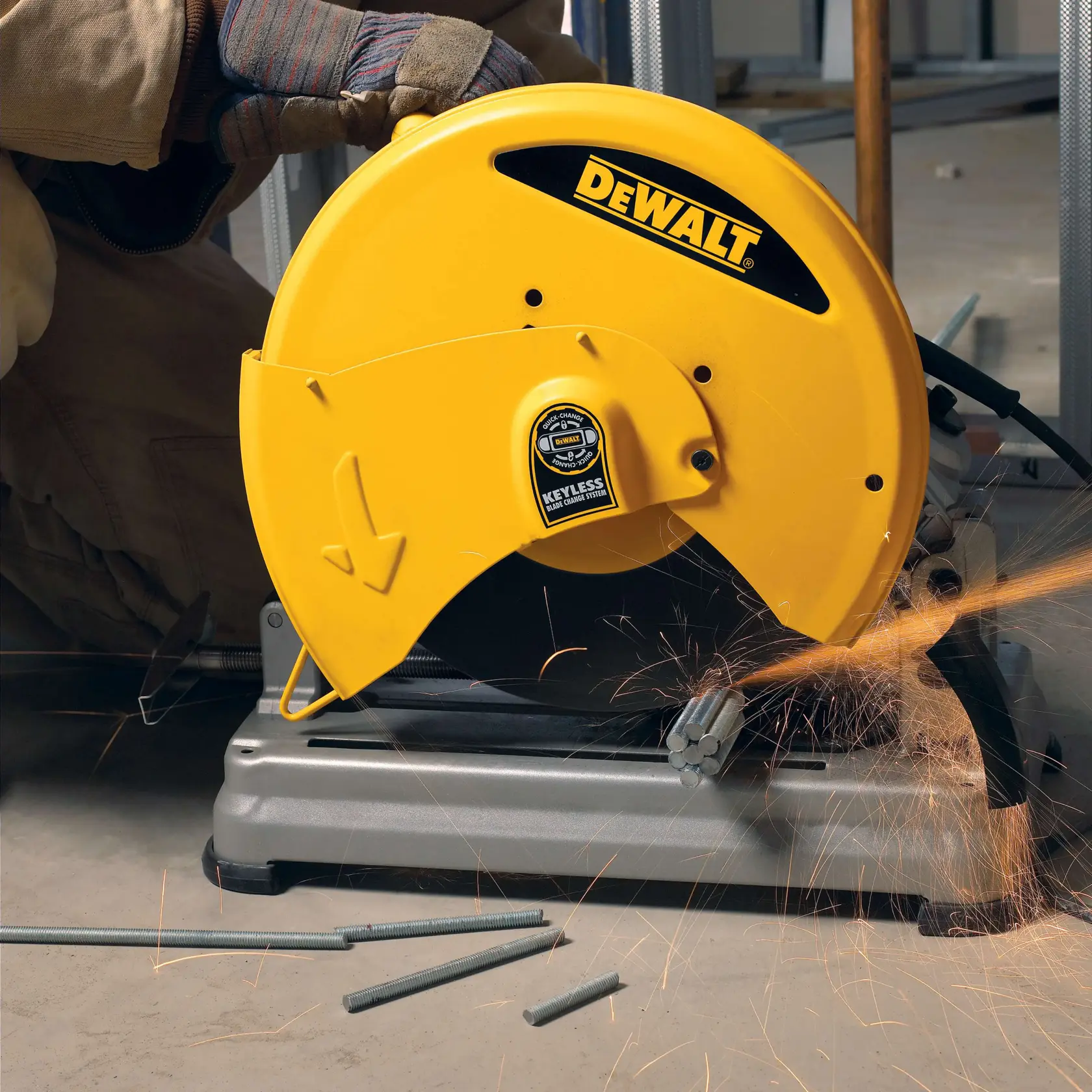 Una persona con equipo de seguridad utiliza una sierra para cortar metal DEWALT para cortar tubos de acero en un entorno industrial. Se pueden ver chispas mientras la sierra está en funcionamiento.