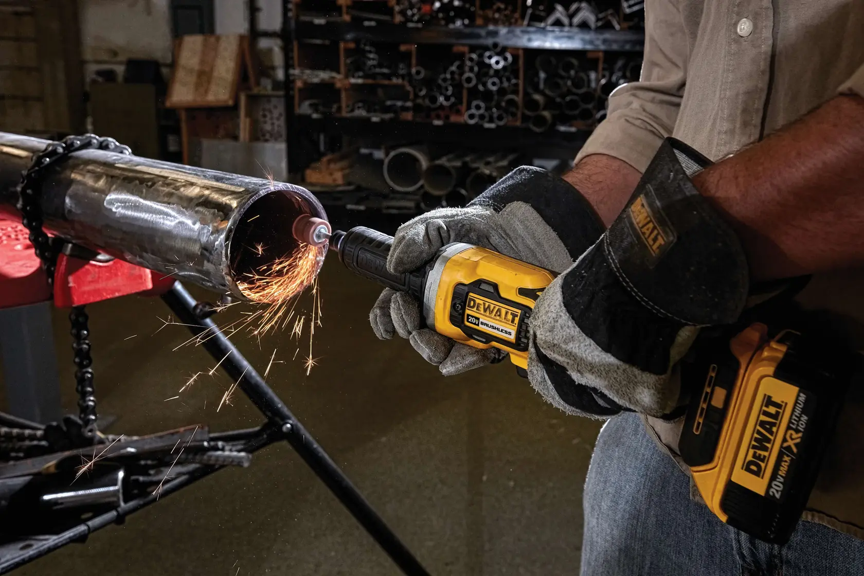 Una persona con guantes protectores utiliza una herramienta inalámbrica DEWALT para lijar o cortar una tubería de metal, generando chispas en un taller industrial.