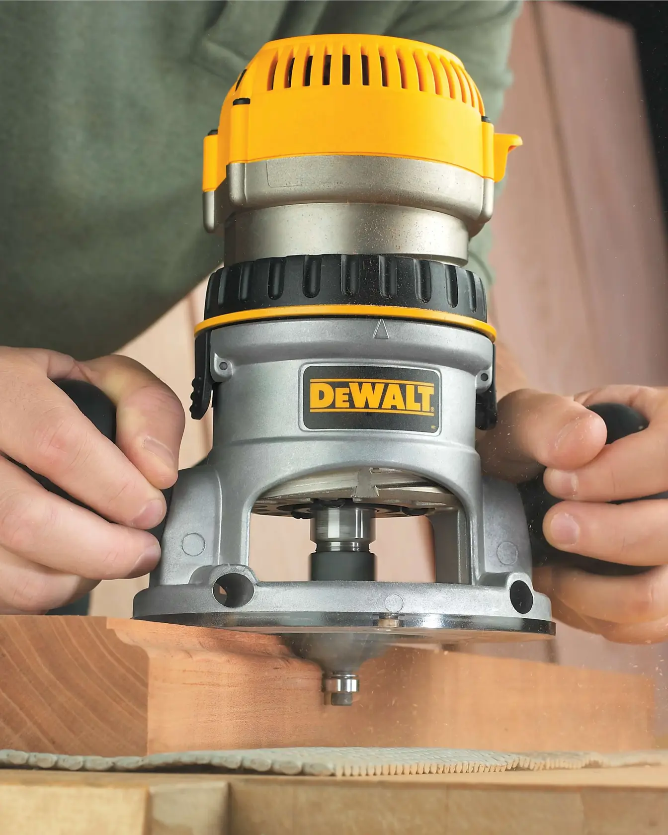 Una persona usando una fresadora de madera DEWALT para dar forma al borde de una tabla de madera.