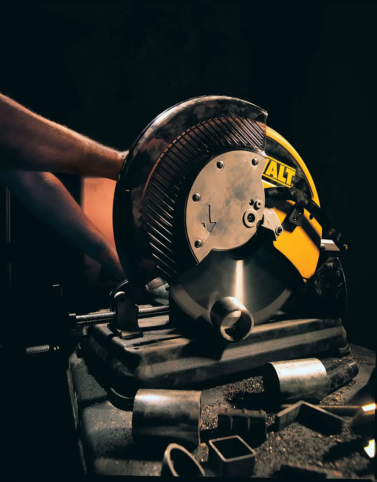 Máquina DEWALT DW872 cortando tubos metálicos, con piezas de metal dispersas en la superficie.