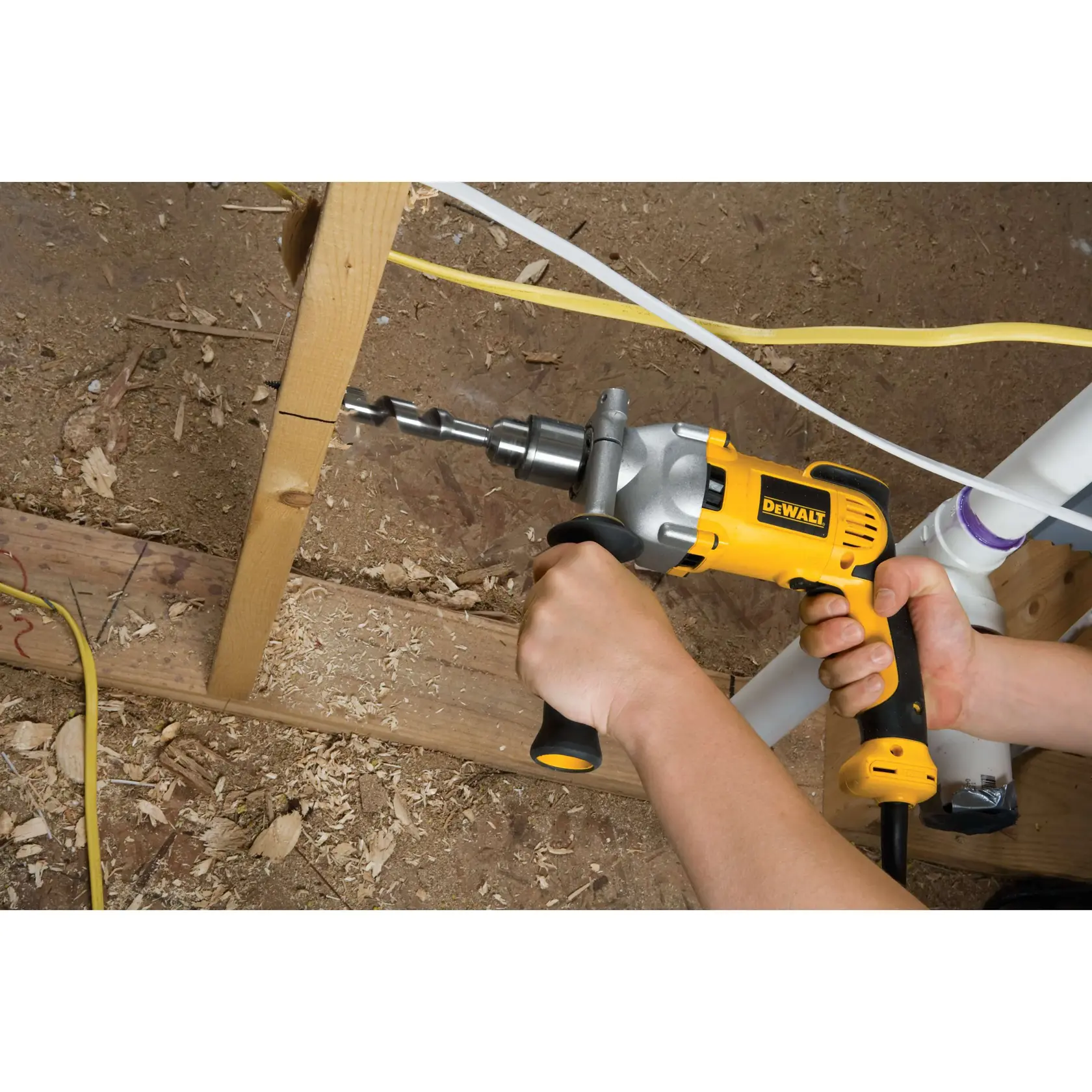Una persona utiliza un taladro eléctrico amarillo DEWALT para perforar un agujero en una viga de madera en una obra de construcción.